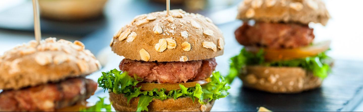 Hamburger met tomaat en sla op zwarte schalen.